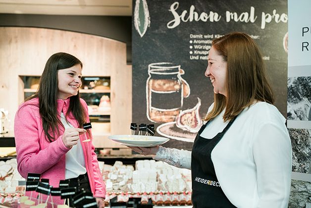 Werbedame verkauft Käse an Kundin im Supermarkt