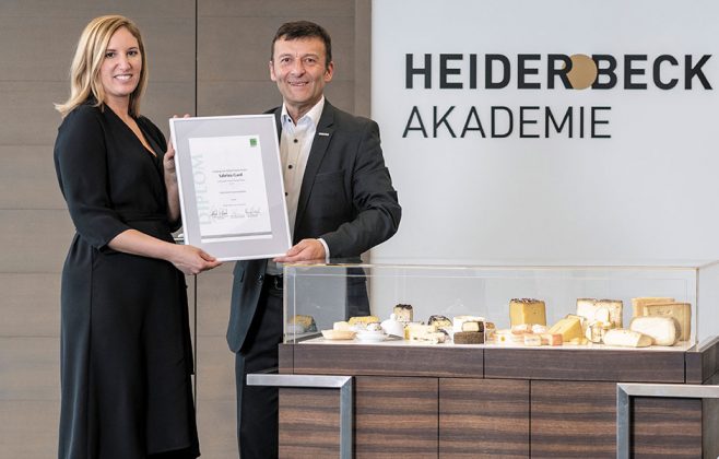 Sabrina und René präsentieren ihr Diplom zum Käsesommelier in der Heiderbeck Akademie, im Vordergrund ein Käsewagen