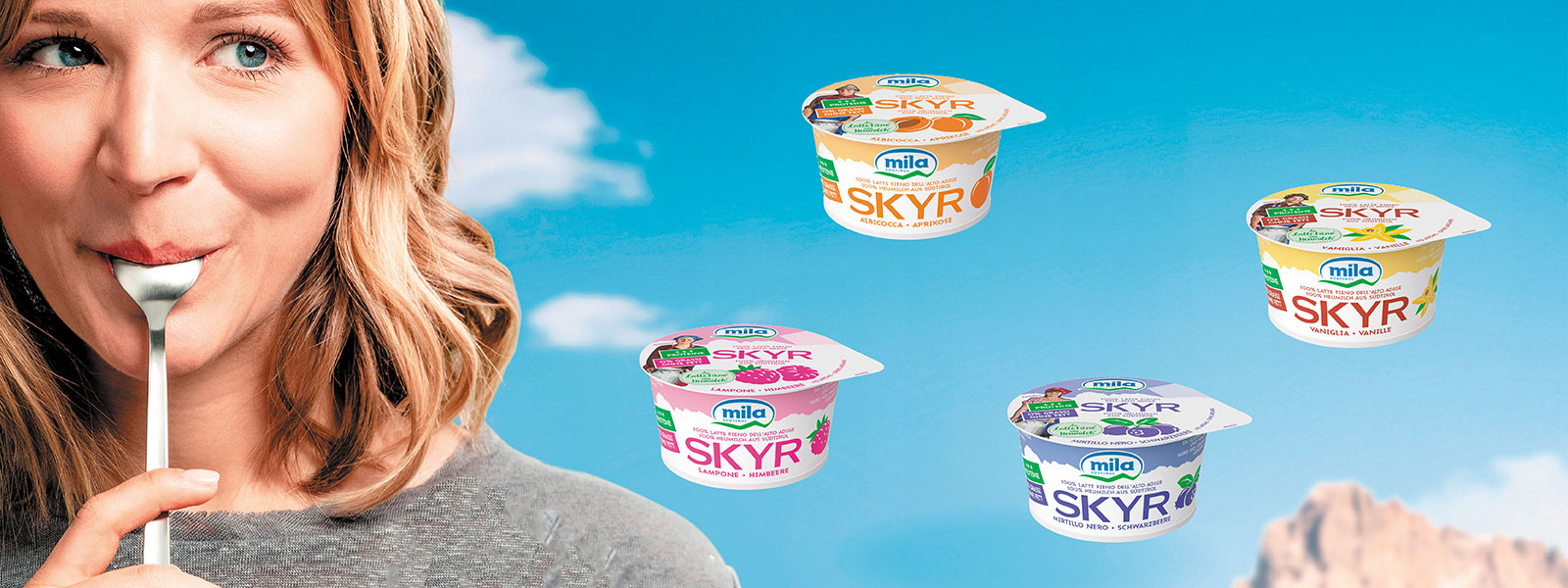 EIne Frau hat einen Löffel im Mund und schaut vergnügt. Um sie herum fliegen Becher von Skyr Milchprodukten.