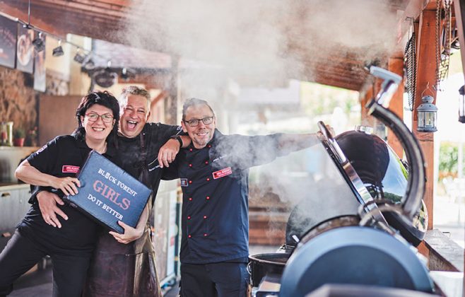Das Grillteam von Forum Culinaire mit Maria Bruder, Gehard Volk und Heiner Haseidl präsentiert sich vor einem brennenden Grill