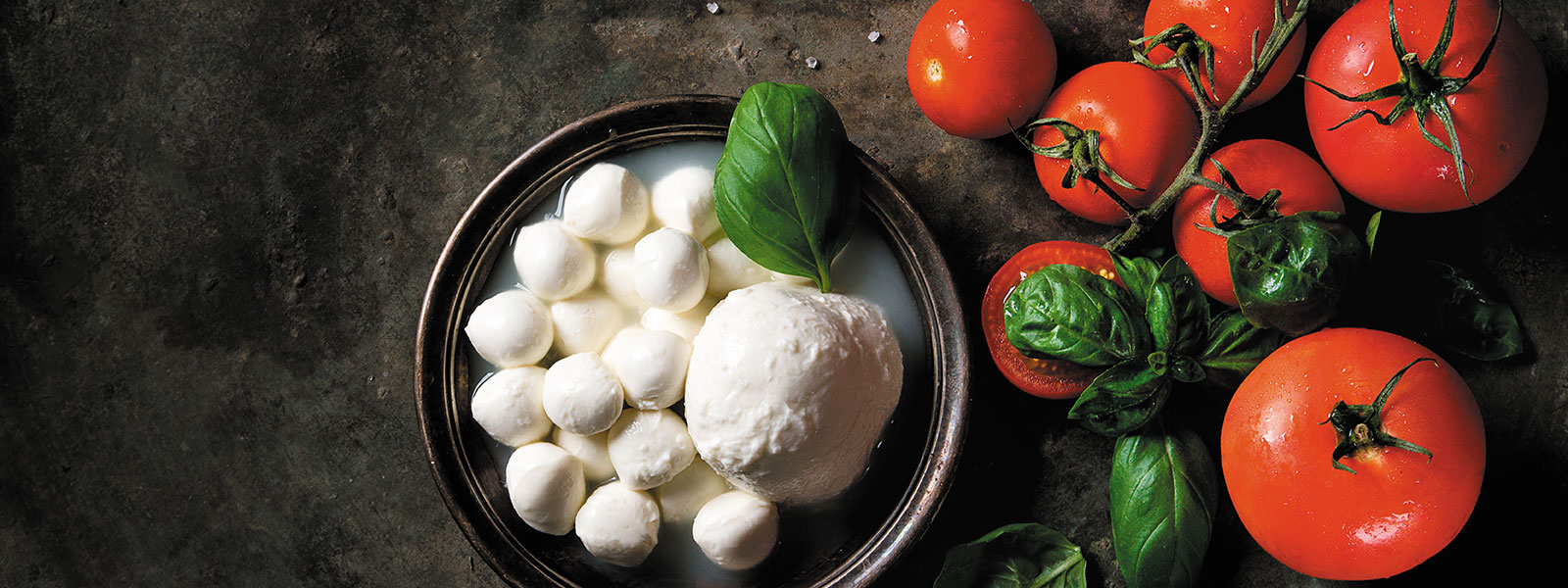 Ein Teller mit Büffelmozzarella wird mit Tomaten und frischem Basilikum angerichtet