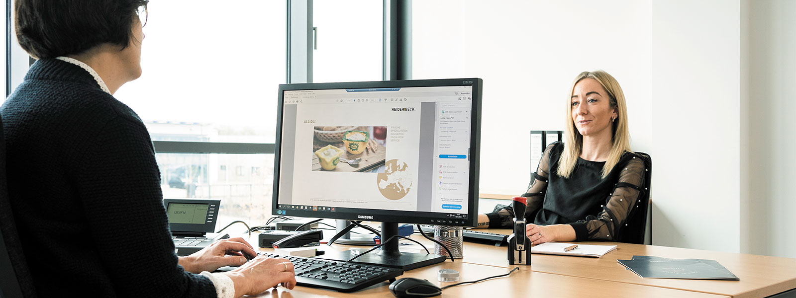 Zwei Frauen sitzen sich in einem Büro gegenüber und arbeiten am Computer